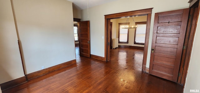 814 W Edwards St, Springfield, IL 62704 - unfurnished bedroom featuring radiator heating unit, a chandelier, dark wood-style flooring, and baseboards
