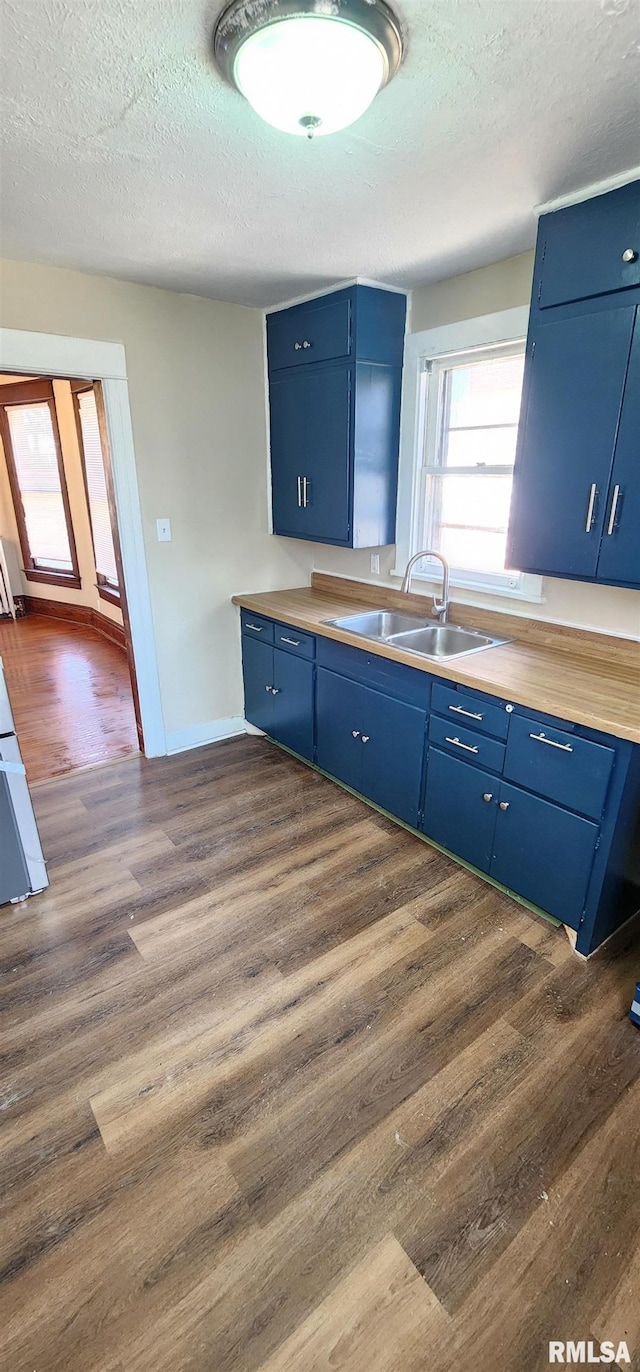 814 W Edwards St, Springfield, IL 62704 - kitchen with blue cabinetry, a sink, a textured ceiling, dark wood-type flooring, and light countertops