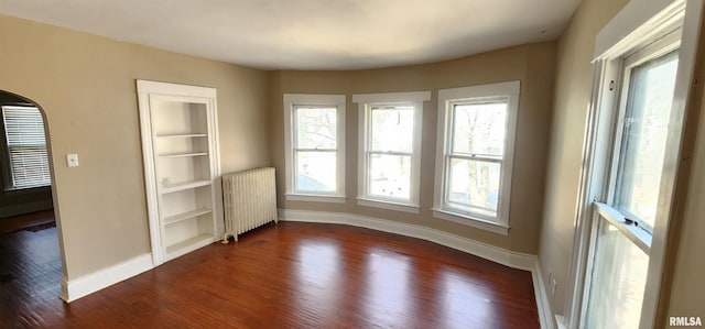 814 W Edwards St, Springfield, IL 62704 - spare room with radiator, dark wood finished floors, baseboards, and arched walkways