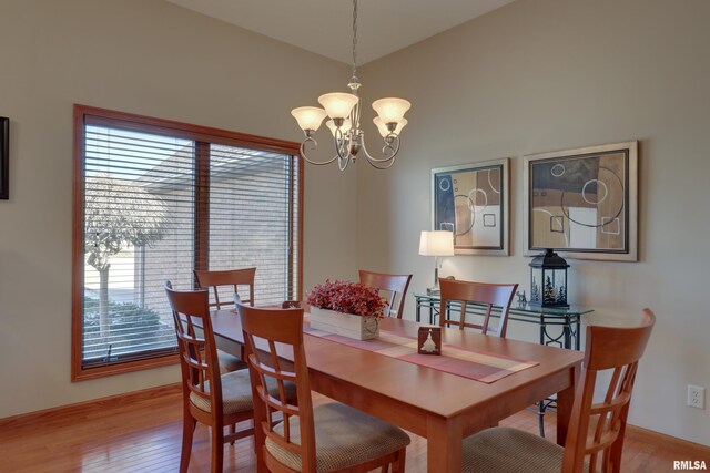 dining space featuring lofted ceiling, wood finished floors, and a notable chandelier