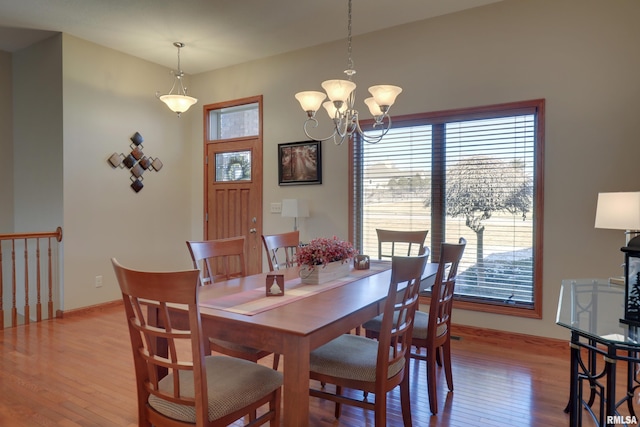 dining area with baseboards, hardwood / wood-style floors, and a notable chandelier