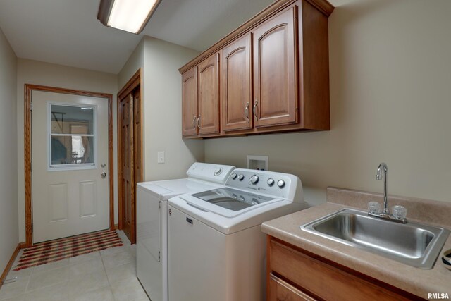 laundry area with cabinet space, light tile patterned floors, washer and dryer, and a sink