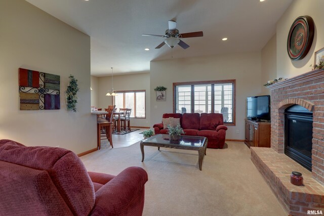 living room with ceiling fan with notable chandelier, a fireplace, baseboards, and light colored carpet