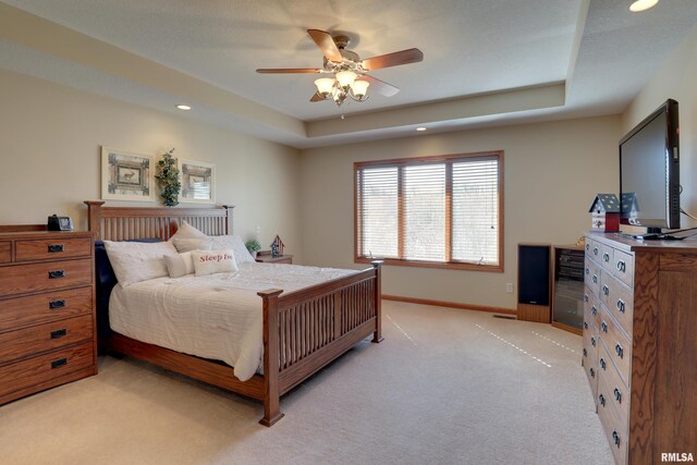 bedroom featuring a tray ceiling, recessed lighting, light colored carpet, a ceiling fan, and baseboards