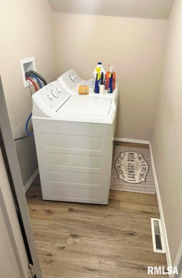 clothes washing area featuring washer and dryer, visible vents, wood finished floors, and laundry area