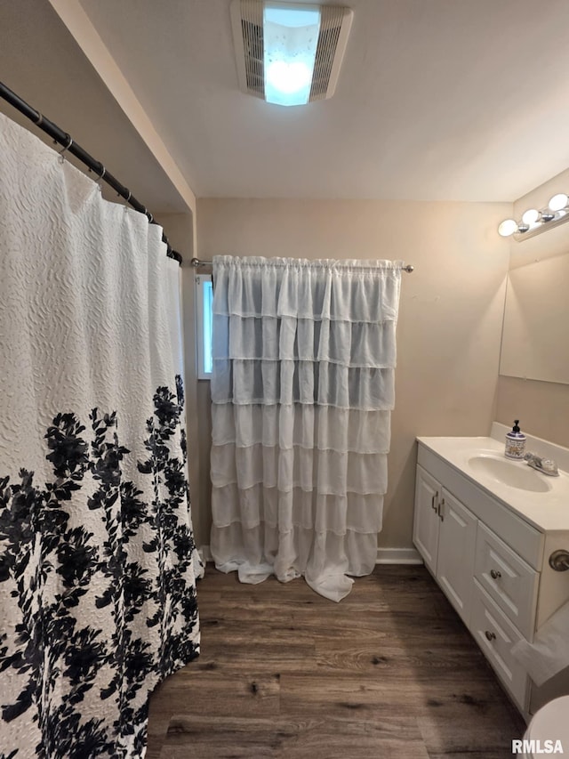 bathroom with vanity, curtained shower, wood finished floors, and visible vents