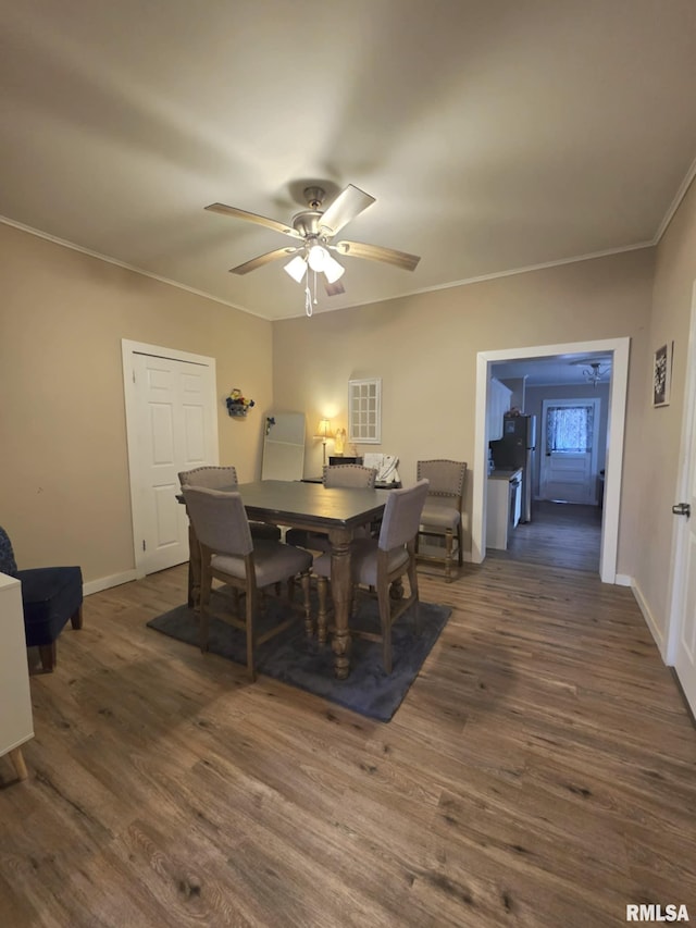 dining space with a ceiling fan, dark wood-type flooring, baseboards, and ornamental molding