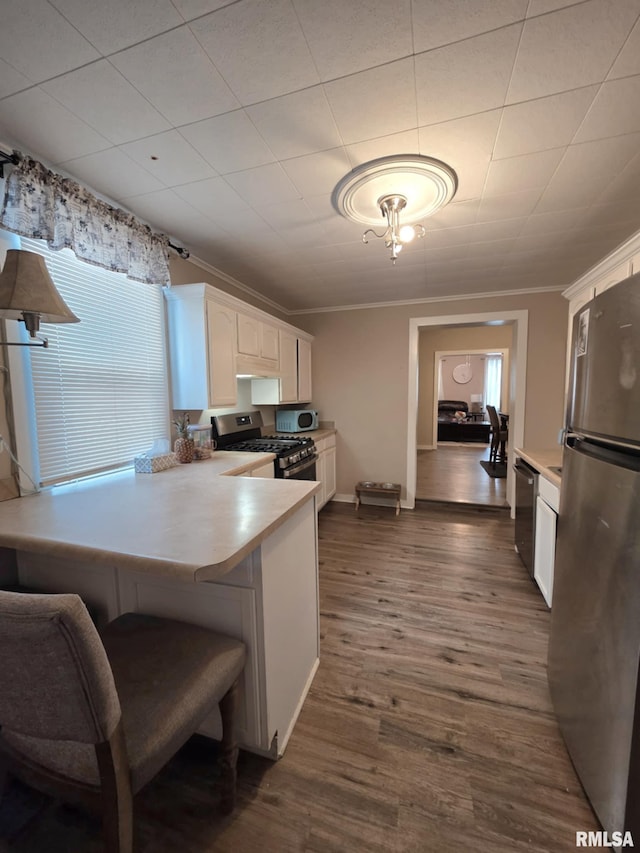 kitchen with crown molding, dark wood-type flooring, light countertops, white cabinets, and stainless steel appliances