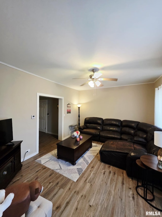 living area featuring a ceiling fan, crown molding, wood finished floors, and baseboards