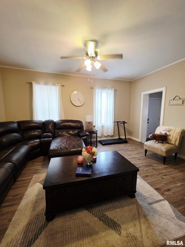 living room featuring a ceiling fan, crown molding, wood finished floors, and baseboards