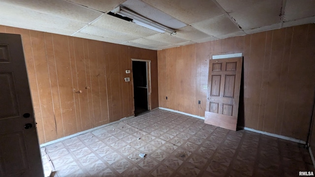 empty room featuring wood walls and tile patterned floors