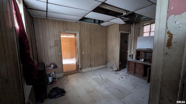 interior space with a paneled ceiling and wood walls