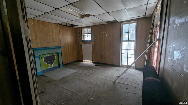 interior space with wood walls and a drop ceiling