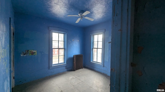 doorway to outside with ceiling fan, a textured ceiling, and radiator heating unit