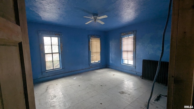 spare room featuring a healthy amount of sunlight, ceiling fan, radiator heating unit, and tile patterned floors