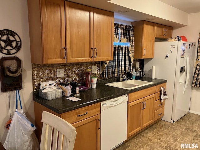 kitchen featuring white appliances, a sink, decorative backsplash, stone finish floor, and dark countertops