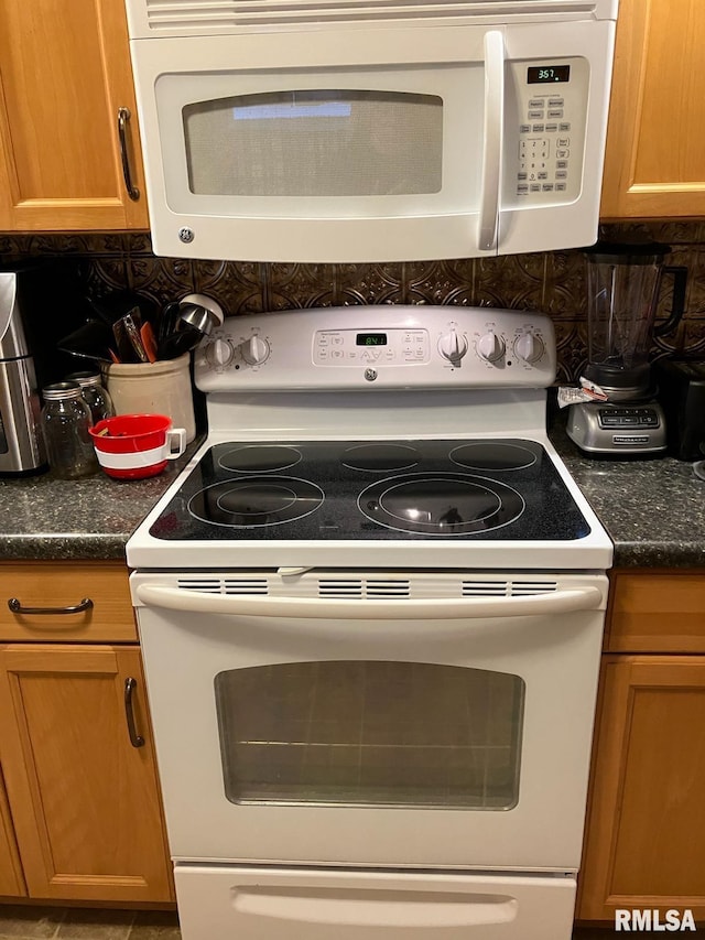 kitchen featuring white appliances, dark stone countertops, and decorative backsplash