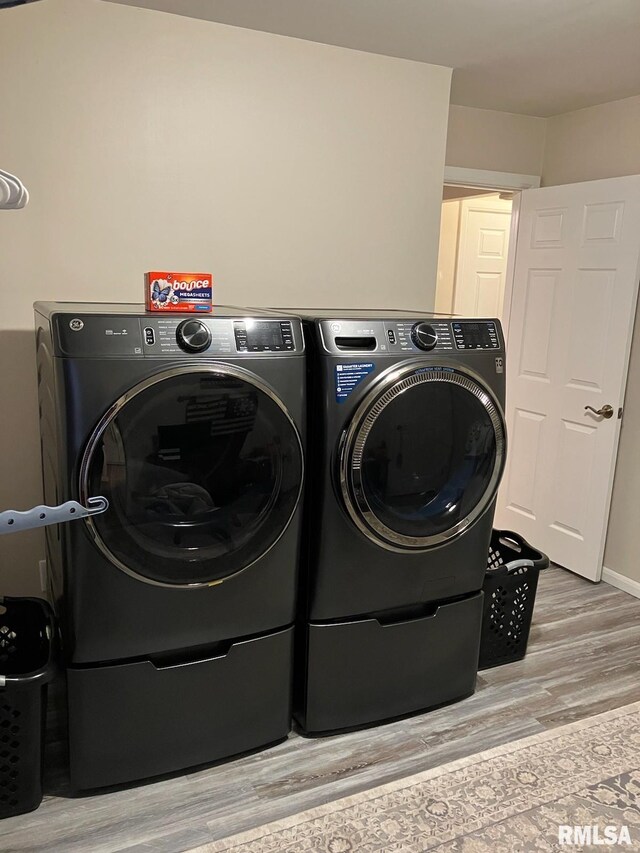 laundry room with light wood-type flooring, laundry area, and washing machine and clothes dryer