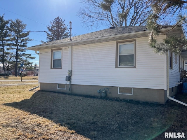 view of side of home featuring a yard and a shingled roof