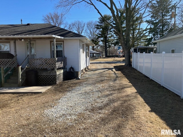 view of home's exterior featuring a porch, a shingled roof, and fence