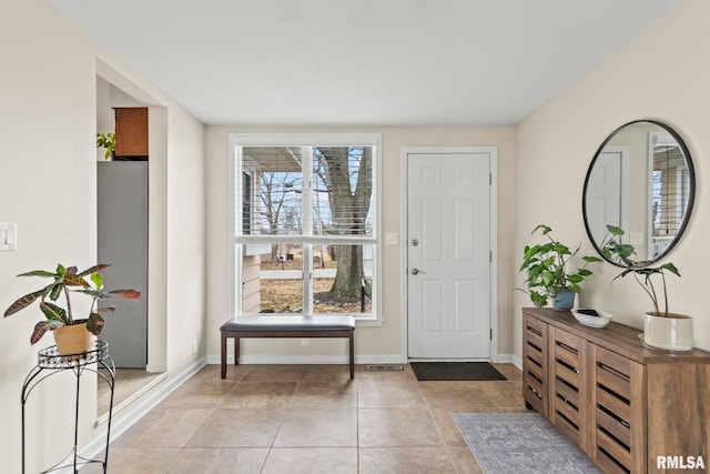 foyer entrance with light tile patterned floors and baseboards