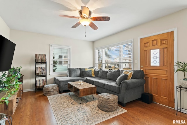 living area with wood finished floors, a ceiling fan, and baseboards