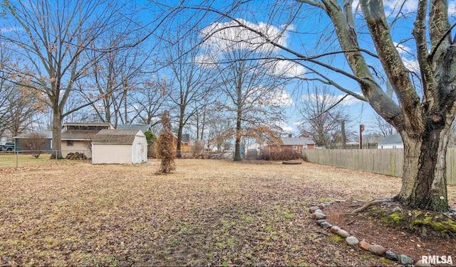 view of yard with a storage shed, a fenced backyard, and an outbuilding