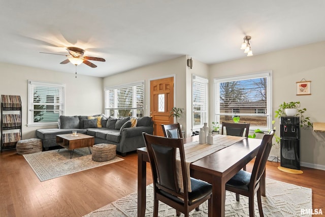 dining area with wood finished floors, a ceiling fan, and baseboards