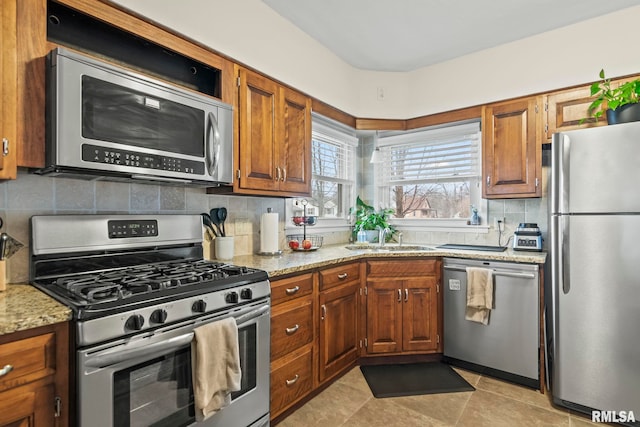 kitchen featuring brown cabinetry, stainless steel appliances, and a sink