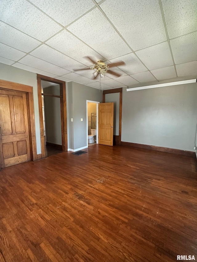 interior space featuring ceiling fan, a drop ceiling, baseboards, and wood finished floors