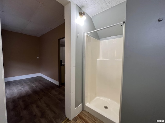 bathroom featuring a shower stall, wood finished floors, baseboards, and a drop ceiling