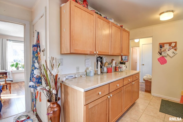 kitchen featuring light countertops, light tile patterned floors, baseboards, and ornamental molding