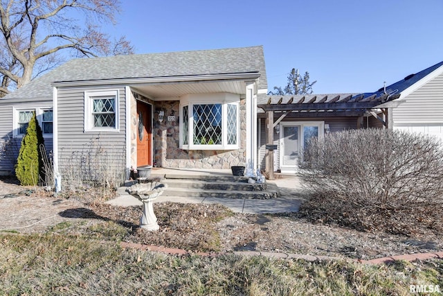 bungalow with stone siding, a pergola, and a shingled roof