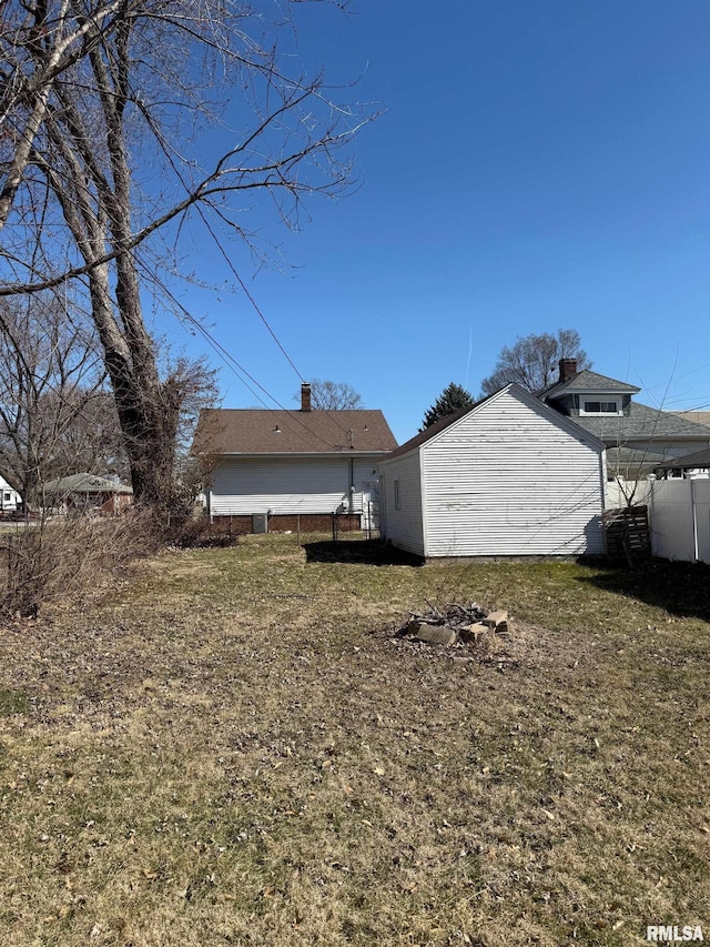 view of property exterior with a lawn, a chimney, and fence