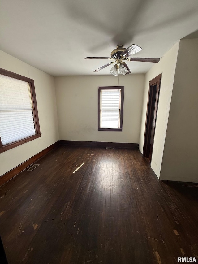 empty room with visible vents, a ceiling fan, baseboards, and hardwood / wood-style flooring