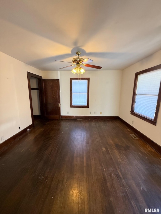 unfurnished room with visible vents, baseboards, dark wood-style floors, and a ceiling fan