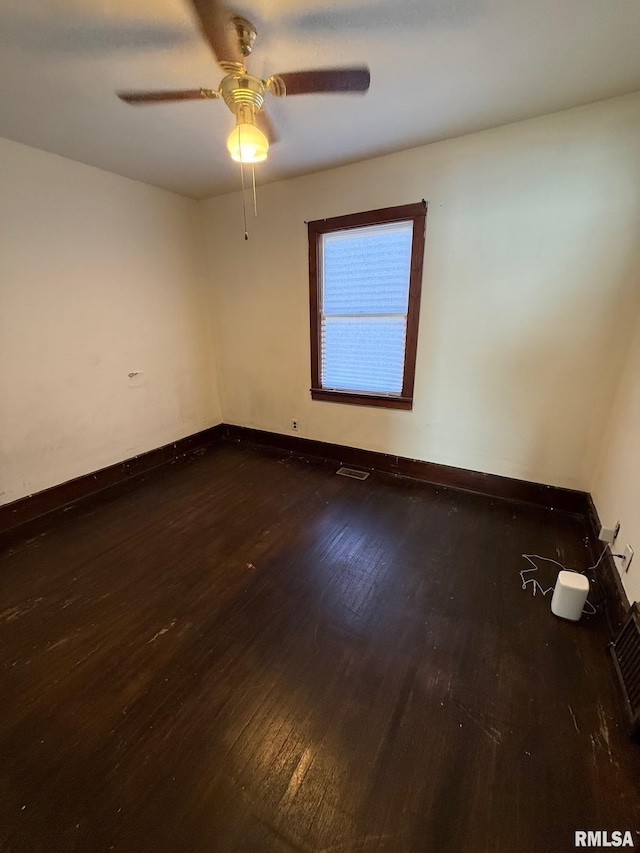 spare room with visible vents, baseboards, dark wood-style floors, and a ceiling fan