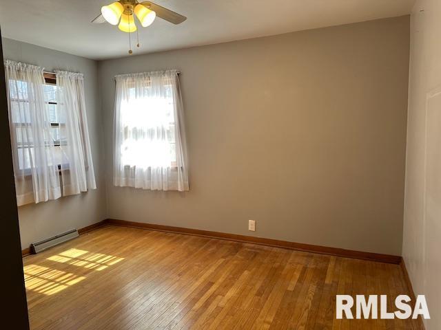 unfurnished room with ceiling fan, a baseboard heating unit, baseboards, and light wood-style flooring