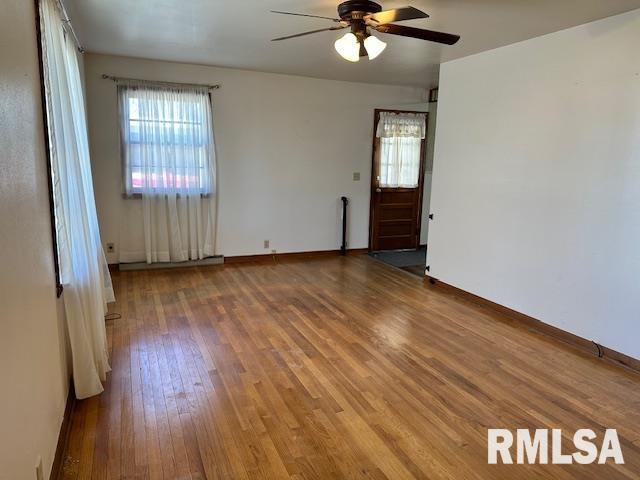 unfurnished room with hardwood / wood-style flooring, a ceiling fan, and baseboards