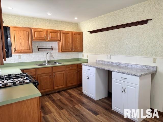 kitchen featuring brown cabinets, a sink, dark wood finished floors, gas stove, and light countertops