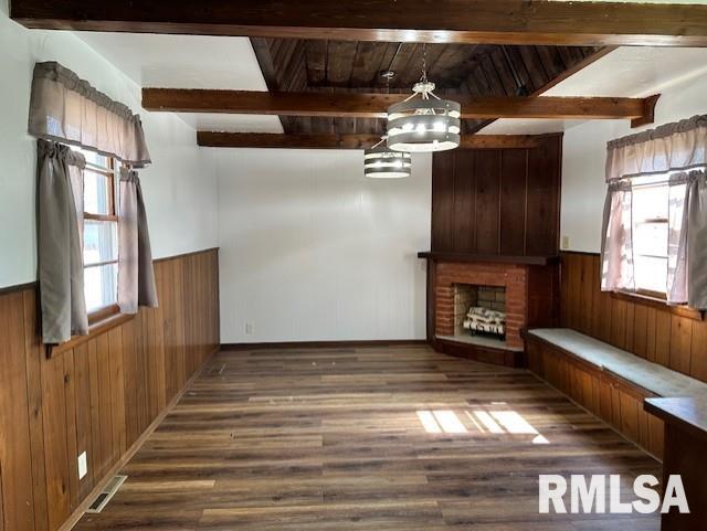 unfurnished living room with visible vents, wooden walls, and wainscoting