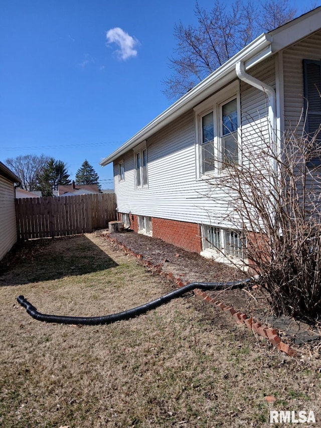 view of home's exterior with a lawn and fence