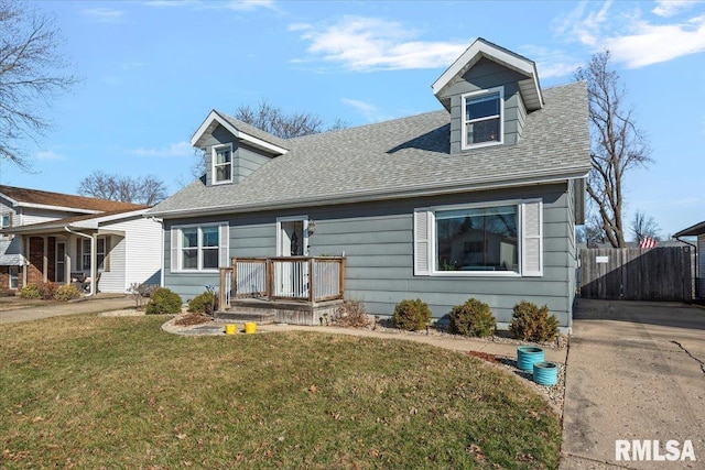 cape cod house featuring a shingled roof, a front yard, and fence