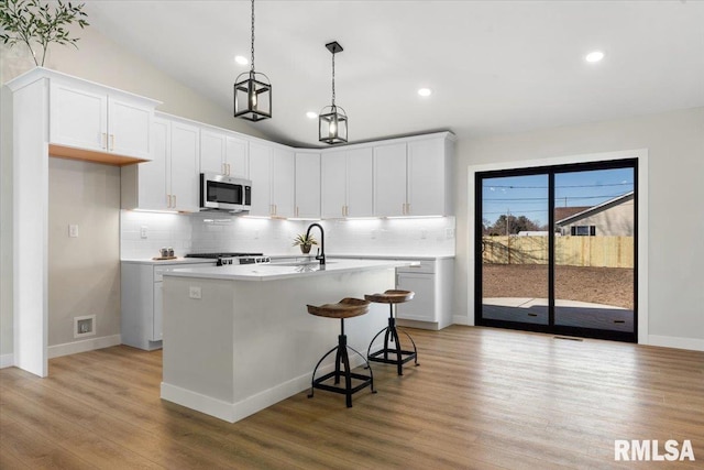 kitchen with a sink, stainless steel microwave, light wood-style flooring, and light countertops