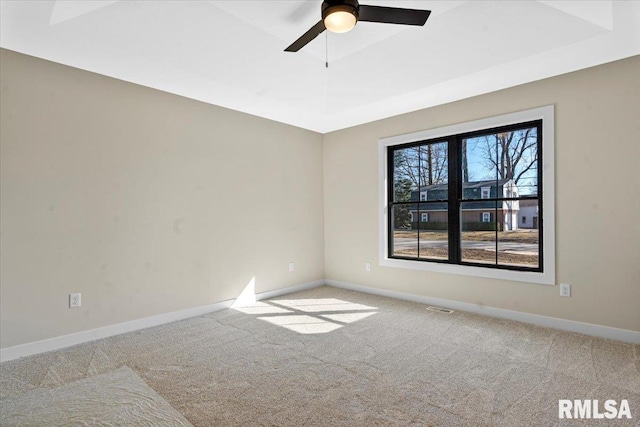 empty room featuring a ceiling fan, baseboards, carpet floors, visible vents, and a raised ceiling