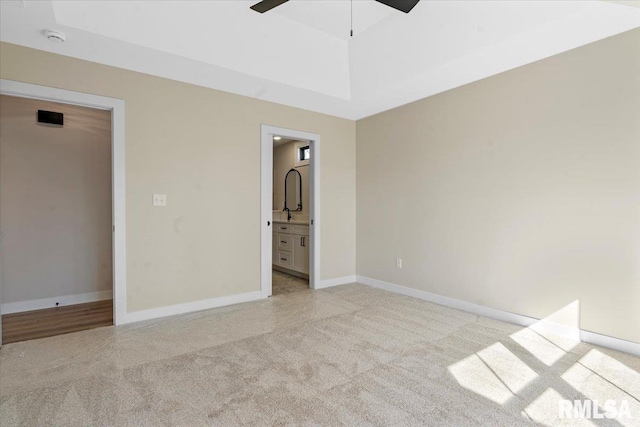 unfurnished bedroom with light colored carpet, a ceiling fan, ensuite bathroom, and baseboards