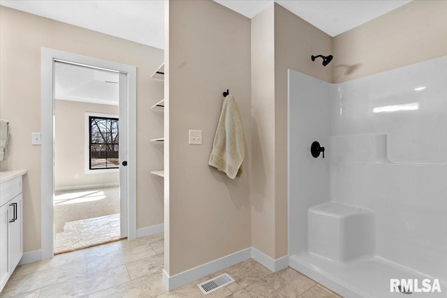 bathroom featuring vanity, baseboards, visible vents, and walk in shower