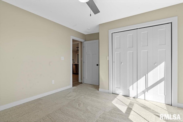 unfurnished bedroom featuring a closet, baseboards, light colored carpet, and ceiling fan