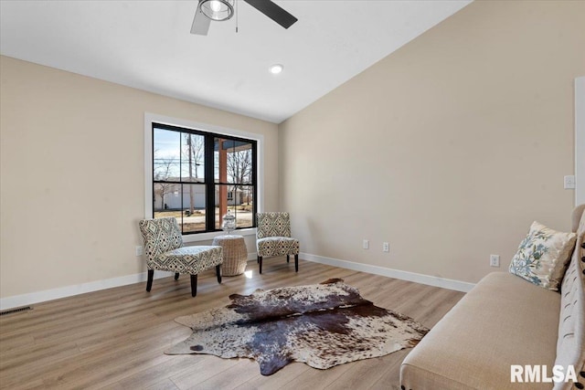 living area with visible vents, light wood finished floors, baseboards, and vaulted ceiling