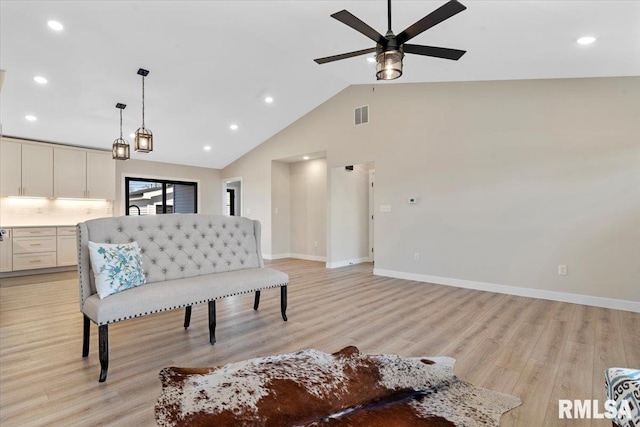 living area with visible vents, ceiling fan, baseboards, light wood-type flooring, and high vaulted ceiling